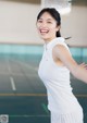 A woman in a white shirt and skirt standing on a tennis court.