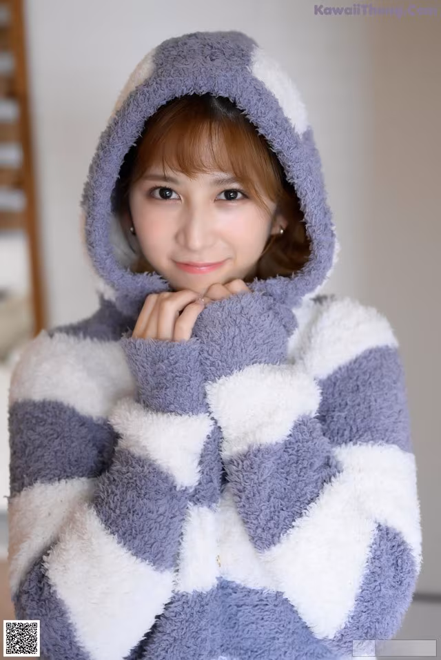 A young woman wearing a gray and white striped hoodie.