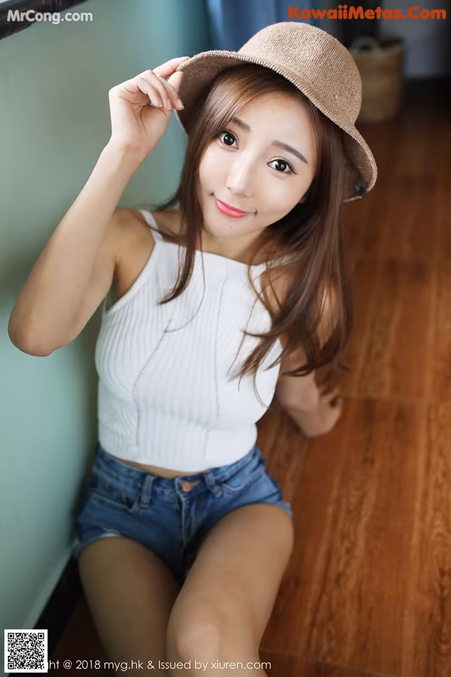 A woman in a white top and blue shorts posing for a picture.