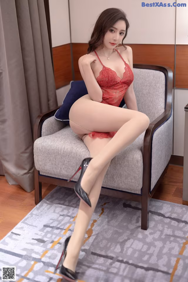 A woman in a red lingerie sitting on a chair.