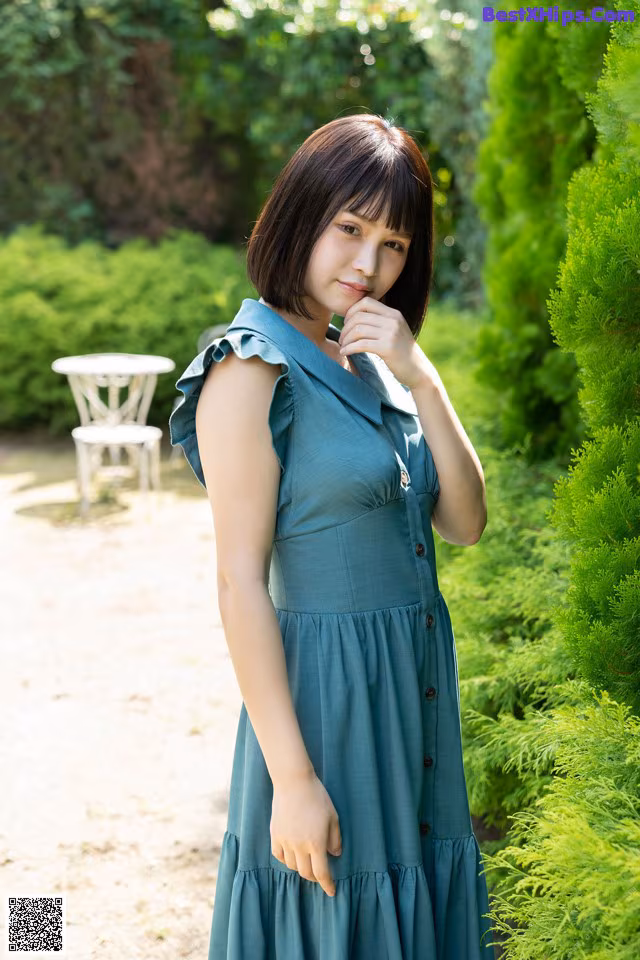 A woman in a blue dress standing in a garden.