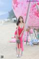 A woman in a pink dress standing on a beach.