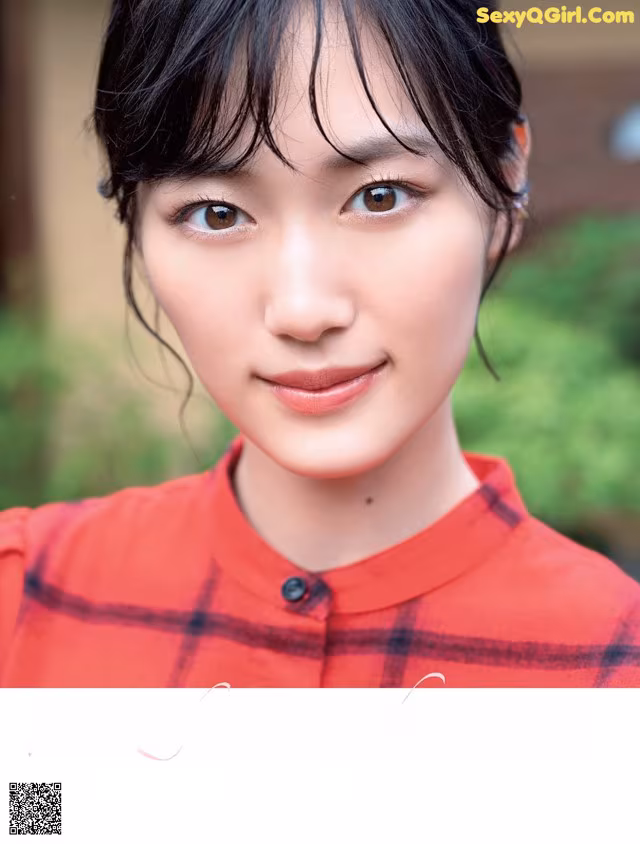 A woman in a red shirt is posing for a magazine.