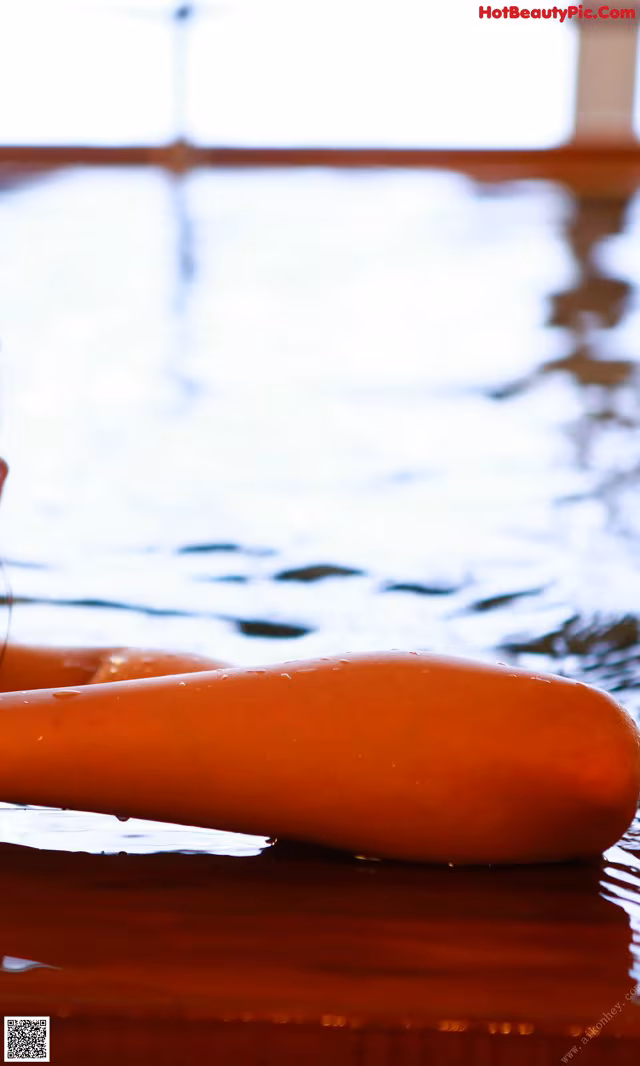A carrot floating in a pool of water. 
