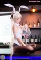 A woman in bunny ears sitting at a bar holding a wine glass.