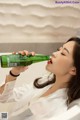 A woman is drinking from a green bottle.