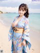 A woman in a blue kimono standing on a beach.