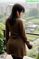 A woman in a brown dress standing on a balcony.