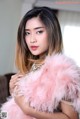 A woman in a pink fur coat posing for a picture.