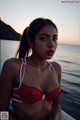 A woman in a red and white bikini sitting on a boat.