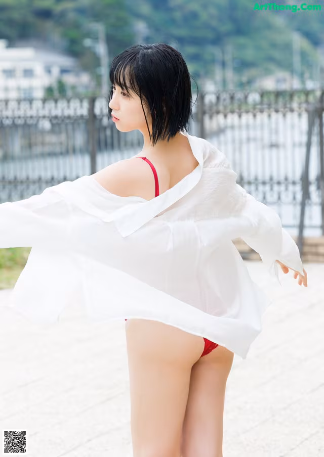 A woman in a white shirt and red bikini posing for a picture.