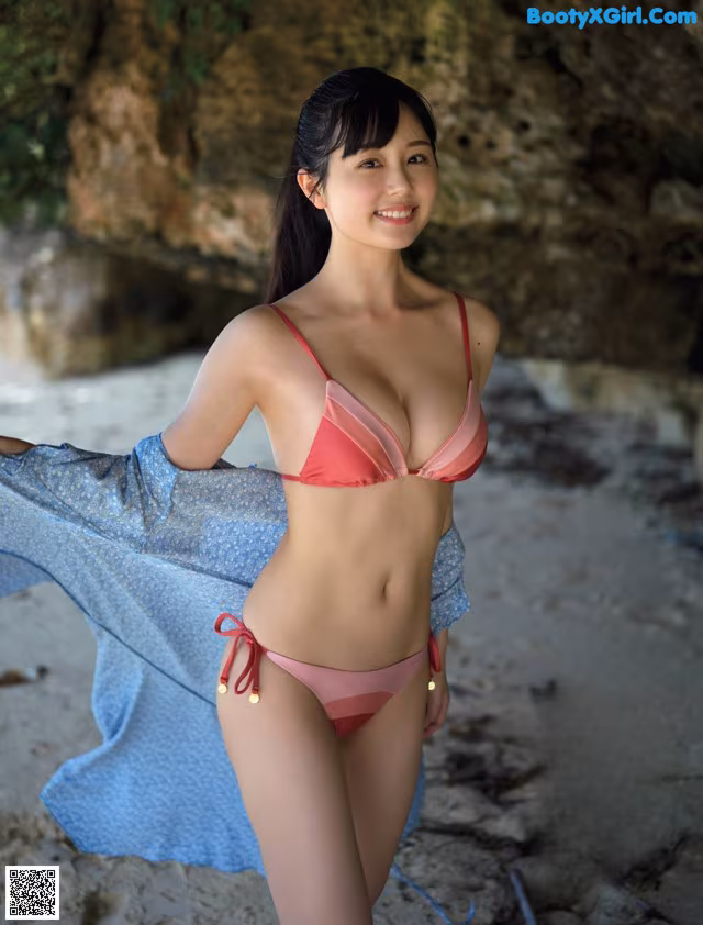 A woman in a pink bikini standing on a beach.