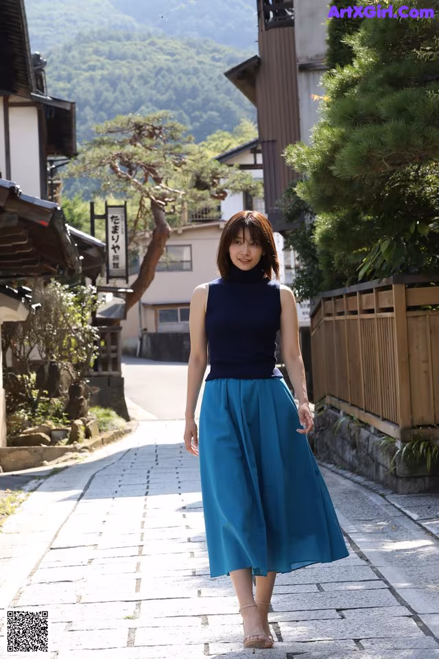 A woman in a blue skirt is walking down a street.