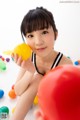 A young woman sitting on the floor holding a yellow ball.