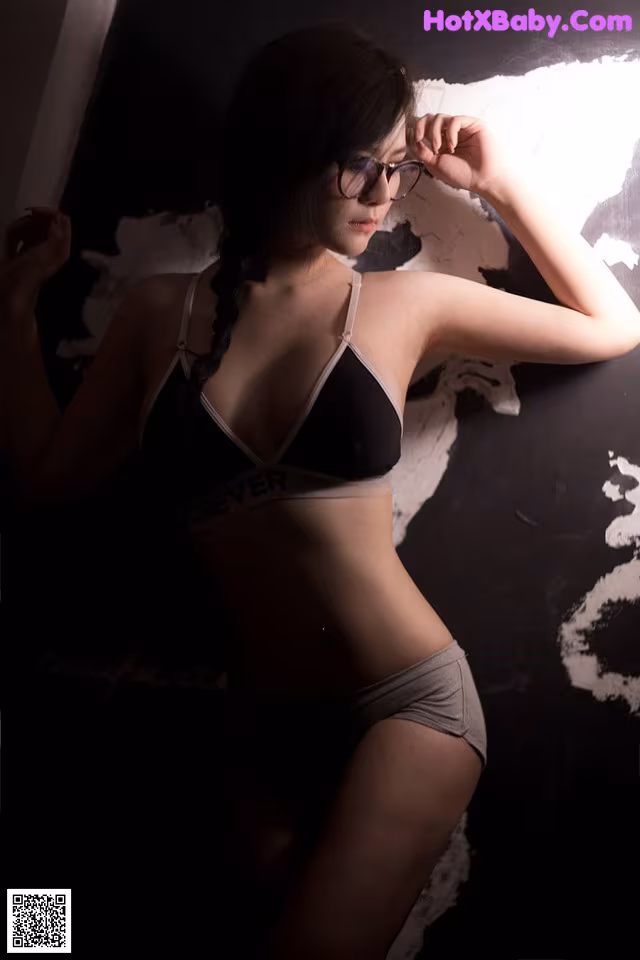 A woman in a black bra and gray panties posing for a picture.