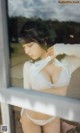 A woman in a white lingerie leaning against a window.