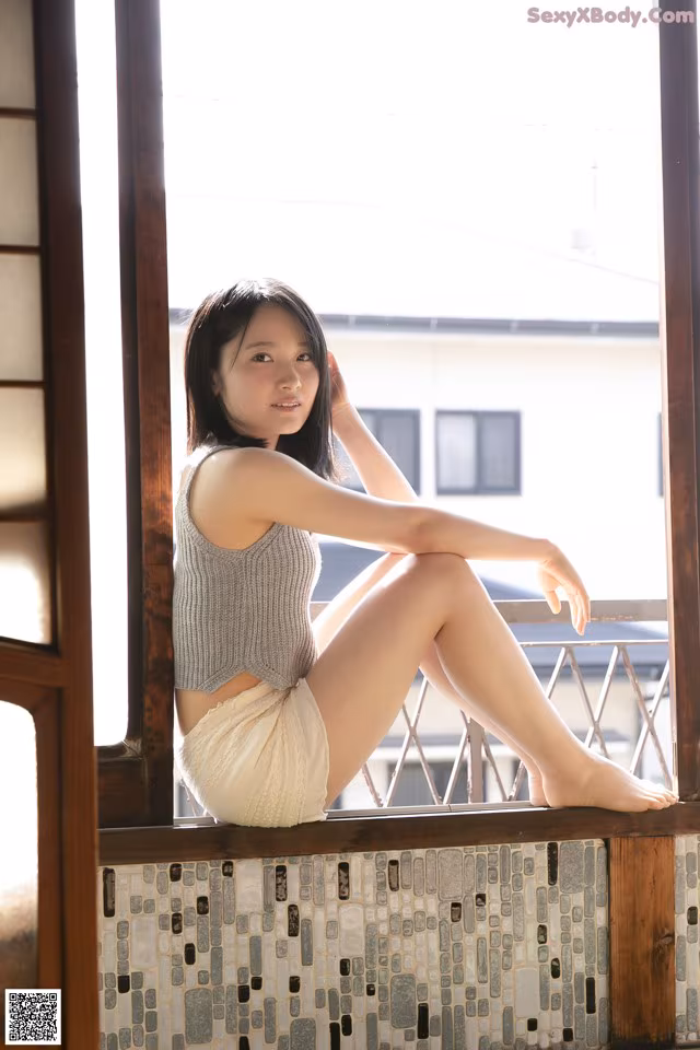 A woman sitting on a window sill with her legs crossed.